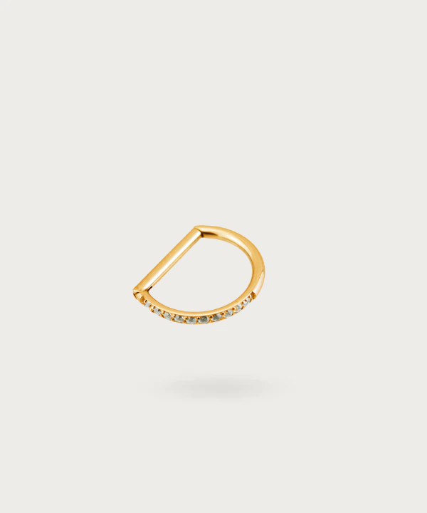Un elegante piercing snug de titanio con circonitas en forma de herradura, brillando suavemente sobre un fondo