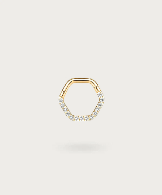 Elegante piercing clicker Maritza de titanio con circonitas en forma de hexágono, brillando suavemente sobre un fondo oscuro