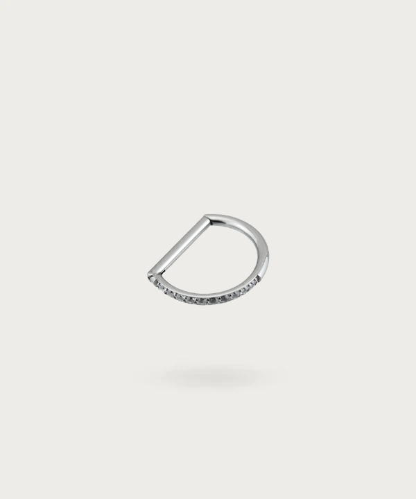 Primer plano del piercing daith Alicia, mostrando su diseño de herradura con circonitas y el seguro cierre en titanio
