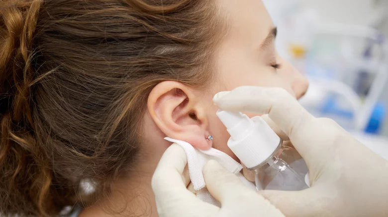 mujer desinfección de un piercing en la oreja