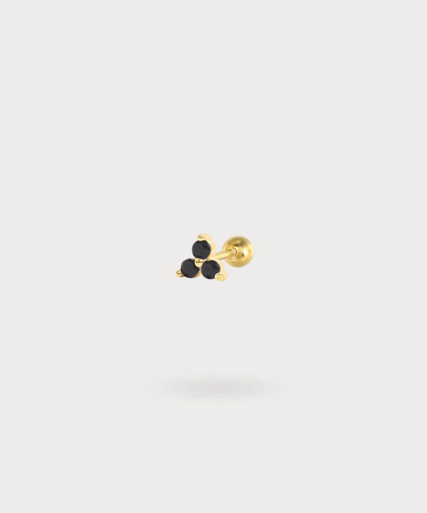 Piercing de tragus en oro adornado con tres zircones negros.